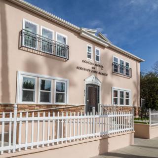 A residential two-story building with white railings and multiple windows.