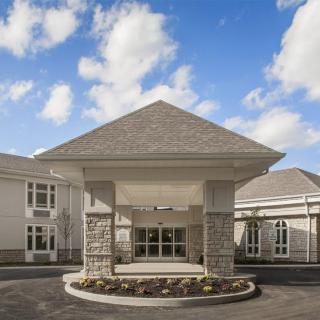 A modern building entrance with a triangular roof against a partly cloudy sky.