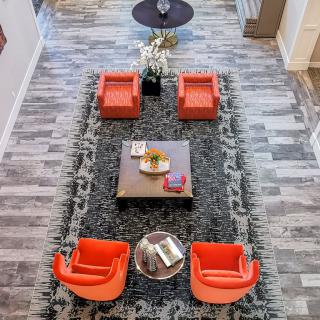 A modern living room with orange chairs and a stylish coffee table viewed from above.