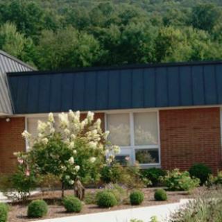 A serene view of a building surrounded by lush greenery and blooming flowers.