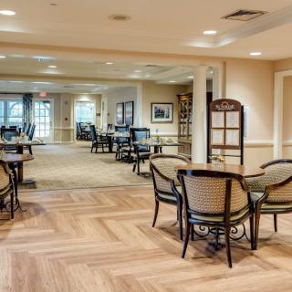 A cozy dining area with wooden flooring and neatly arranged tables and chairs.