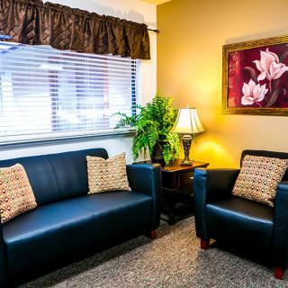 A cozy living room with a sofa, armchair, and warm lighting.