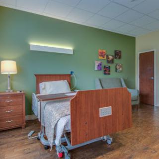 A well-designed hospital patient room featuring a hospital bed, comfortable seating, and decorative elements for a welcoming atmosphere.