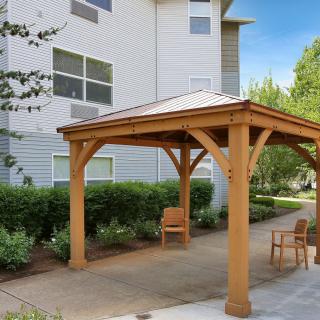 A wooden gazebo with outdoor chairs in a garden patio area.