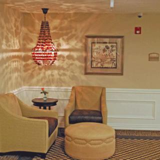 A cozy seating area with two chairs, an ottoman, and a small table under a decorative hanging lamp.