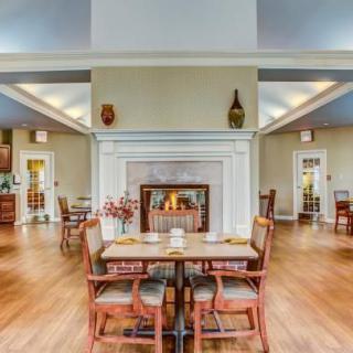 A cozy dining room with a central fireplace and neatly arranged tables and chairs.