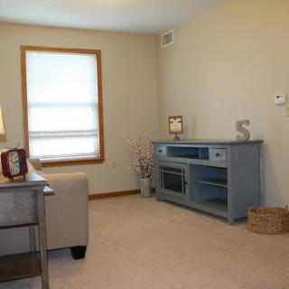 A cozy living room with a sofa, blue cabinet, and a window letting in natural light.