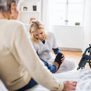 A caregiver assists an elderly person with mobility at home.