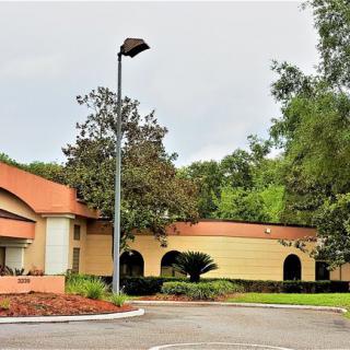 A view of a building surrounded by trees with a nearby parking area.