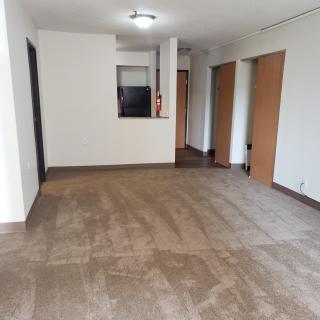An empty apartment living room with hardwood floors and multiple doors.