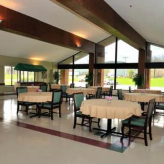 A spacious dining area with tables and chairs, featuring large windows that allow natural light to fill the room.