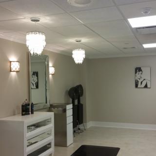 A modern salon interior with elegant chandeliers and a large mirror.