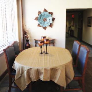 A cozy dining area featuring a round table adorned with a beige tablecloth, surrounded by stylish chairs and complemented by decorative wall art.