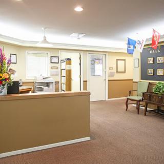 A well-lit reception area with a desk, chairs, and flags on display.