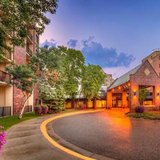 A welcoming hotel entrance surrounded by lush greenery and warm evening lights.