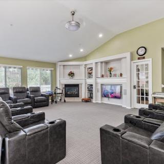 A spacious and inviting living room featuring comfortable black seating, a cozy fireplace, and plenty of natural light.