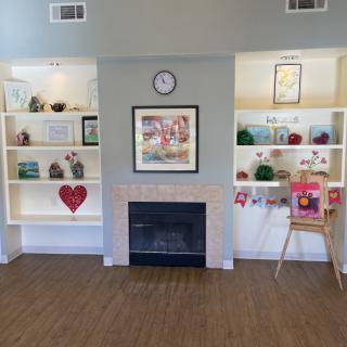 A cozy living room with a central fireplace, flanked by decorated shelves and a clock above.