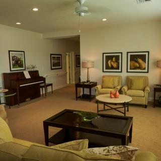 A cozy living room with a piano, comfortable seating, and artwork on the walls.