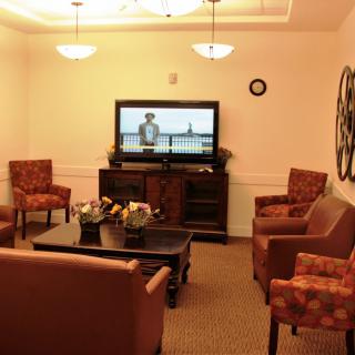 A cozy living room featuring a TV, several chairs, and a coffee table.
