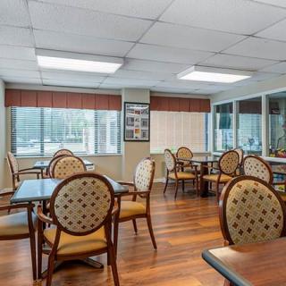 A spacious and well-lit dining area with multiple tables and chairs on a wooden floor.