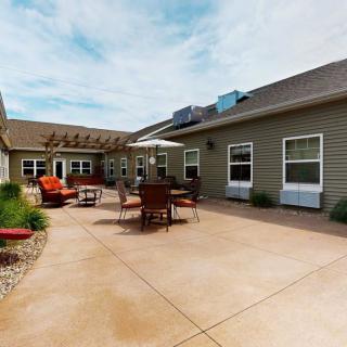 A spacious courtyard with patio furniture and an umbrella, surrounded by a building.