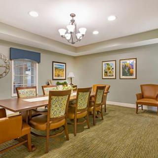 A well-lit dining or conference room with a large table, surrounded by chairs and decorated with artwork on the walls.
