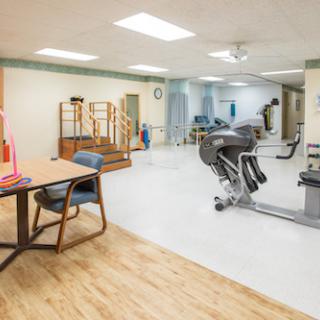 A spacious physical therapy room equipped with exercise machines and rehabilitation tools.