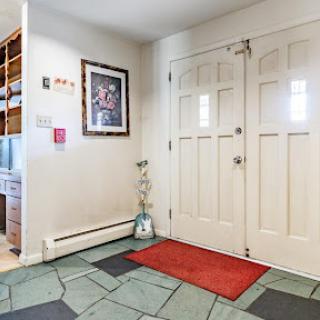 A welcoming entrance featuring a tiled floor, decorative wall art, and a bright double door.