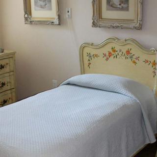 A vintage-style bedroom with a single bed and floral headboard, complemented by framed art on the walls.