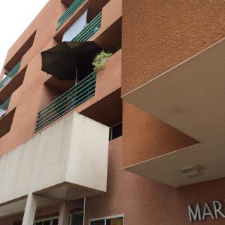 A modern apartment building with balconies featuring an umbrella.