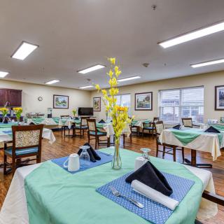 A well-decorated dining area with neatly set tables, featuring yellow flowers and folded napkins.