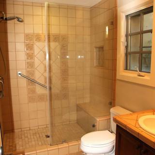 Modern bathroom with a glass-enclosed shower and tiled walls.