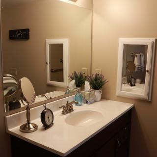 A neatly organized bathroom with a sink, mirror, and decorative items.