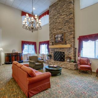 A spacious living room with a stone fireplace, elegant chandelier, and comfortable seating arrangement.