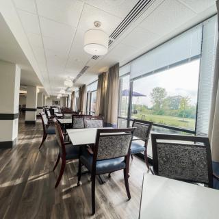 A modern dining area with large windows and neatly arranged tables and chairs.