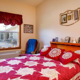 A cozy bedroom featuring a bed with a red and white patterned quilt, decorated walls, and a large window.