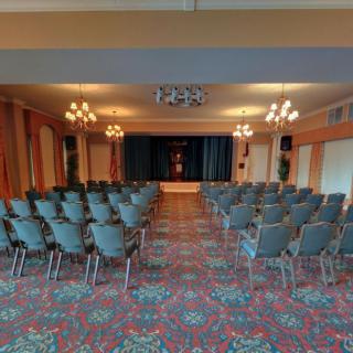 An empty conference room set up with rows of chairs facing a stage.