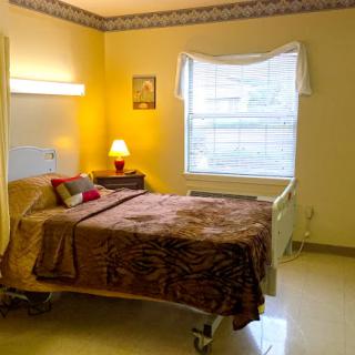 A cozy hospital room featuring a patient bed, bedside lamp, and bright window.