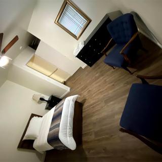 A minimalist bedroom with a single bed, wooden flooring, and modern furniture.
