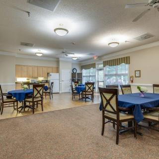 A spacious community dining area with tables and chairs, adjacent to a kitchen space.