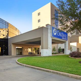 The entrance of a modern hotel, featuring a prominent sign and well-kept landscaping.