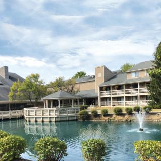 A scenic view of a resort building with a pond and fountain in front.