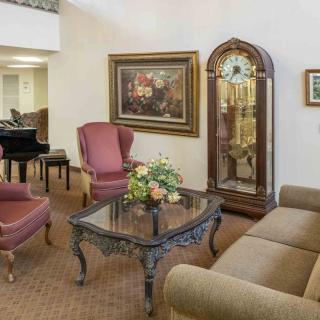 A cozy living room featuring a grand piano, elegant furniture, and decorative elements.