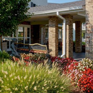 A scenic garden with vibrant flowers and a bench in front of a building.