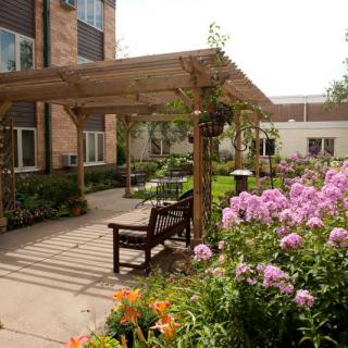 A serene garden setting with a pergola, benches, and vibrant flowers.