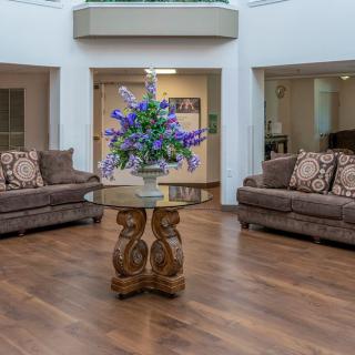 A spacious lobby with plush sofas and a centerpiece coffee table adorned with a flower arrangement.