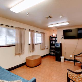 A cozy waiting area featuring comfortable seating, a television, and natural light from the windows.