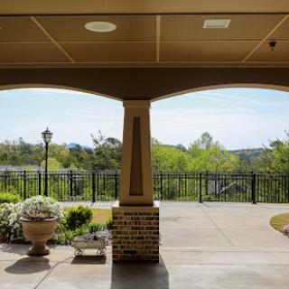 A serene view from a covered porch, showcasing lush greenery and a distant landscape.