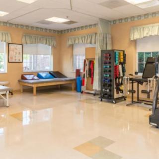 A spacious rehabilitation center equipped with various therapy tools and exercise machines.