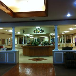 A spacious hotel lobby featuring a central reception desk and modern lighting.
